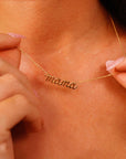 Woman wearing a 14k solid gold “mama” script necklace with a delicate chain, styled as a dainty and meaningful gift for new moms.