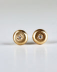 A pair of gold stud earrings with a small, round diamond in the center of each earring.