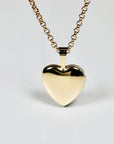 A gold heart-shaped locket pendant on a gold chain necklace.