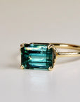 Emerald cut green tourmaline ring set east-west in 14k gold, displayed on a white background as a bold gemstone statement ring.