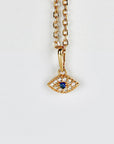 A dainty 14k gold necklace featuring a sapphire center surrounded by CZ diamonds in an evil eye design, shown on a white background.