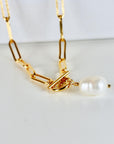 Close-up of a natural baroque pearl pendant hanging from a gold-filled paperclip chain with a toggle clasp, displayed on a white background.