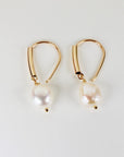 Gold filled dangle earrings featuring large natural baroque pearls with organic shapes, displayed on a white background.
