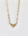 Tiny 14k solid gold bow necklace with twisted ribbon design, displayed on a white background.