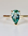 Pear-cut seafoam green tourmaline ring set in solid 14k yellow gold, photographed on a clean white background.