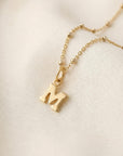 Gold filled satellite chain necklace with a small letter pendant on a white background.