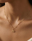 Woman wearing a dainty gold initial necklace with bead chain