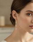 Gold filled pearl drop earrings worn on ear with zircon stud detail