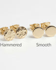 Flat lay of two pairs of tiny gold filled circle stud earrings, one pair hammered texture and one smooth finish, minimalist 5mm disc studs