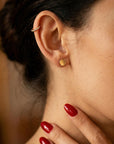 Model wearing minimalist gold coin stud earrings to show size and scale on earlobe.