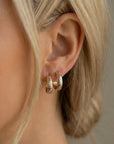 Model wearing small gold filled hoop earrings with floral pattern, chunky open hoop design, minimalist jewelry