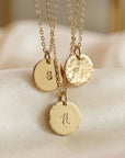 Three gold necklaces with hammered disc pendants, each featuring a different initial: S, V, and H.