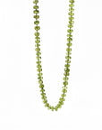 Hand knotted peridot August birthstone necklace on silk with gold filled lobster clasp laid flat on white background.
