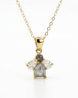 A close-up of a gold chain necklace with a cluster pendant featuring a gray round diamond, a gray rectangular diamond, and two clear pear-shaped diamonds.