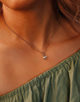 A rose gold chain necklace with a small cluster pendant featuring a rectangular diamond and two pear-shaped diamonds, worn on a person&