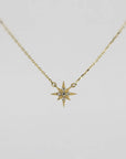 A gold chain necklace with a small, flat, eight-point star pendant, encrusted with tiny clear stones, against a plain white background.