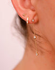Close-up of a human ear wearing a tiny gold trinity stud in the uppermost cartilage piercing.