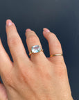 A straight-on view of the hand wearing the gold ring with the large light blue gemstone on the ring finger.