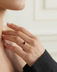 A gold ring with a dark red marquise-cut gemstone worn on a person&