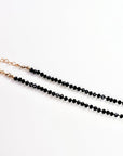 A close-up of a black beaded necklace strand connecting to a gold chain and clasp.