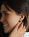 Profile view of a smiling woman wearing a small gold star stud earring in her earlobe.