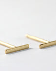 Two gold bar stud earrings shown angled against a plain white background.