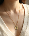 Close-up of a woman wearing a cream sweater and the gold-filled engraved husky coin necklace.