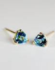 Two blue trillion-cut gemstone stud earrings shown at a slight angle on a neutral background.