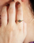 Close-up of a hand with a colorful multi-stone gold ring on the ring finger.