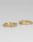 Two small gold pave diamond hoop earrings shown close up on a light surface.