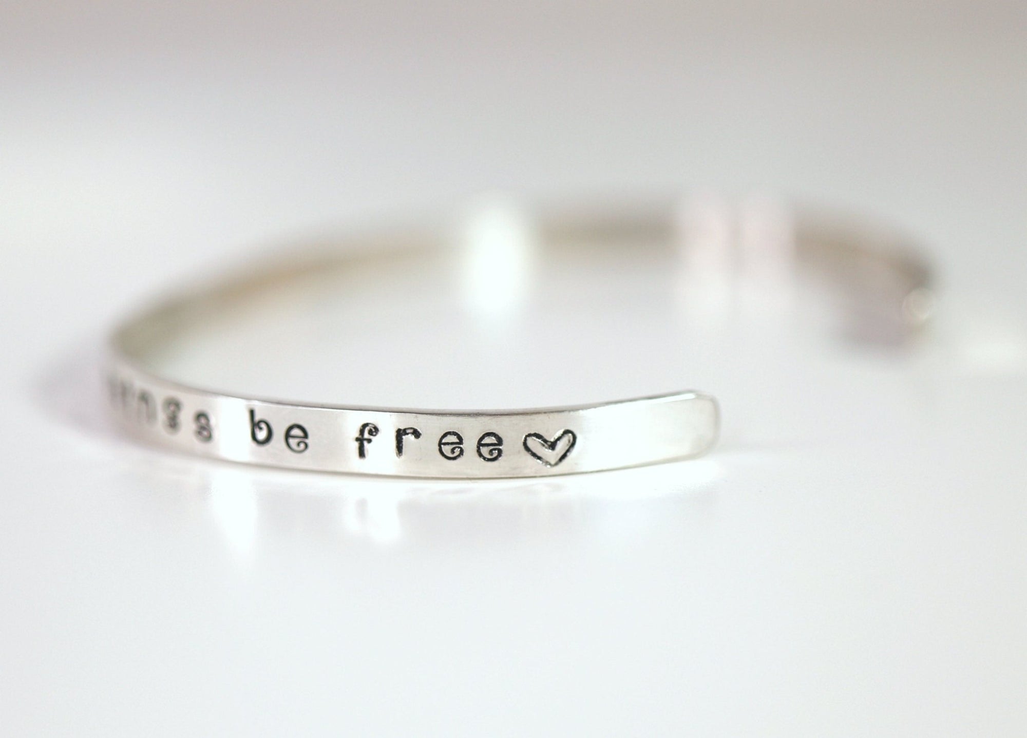 Silver bangle bracelet with the words &amp;quot;things be free&amp;quot; and a heart symbol engraved on it.