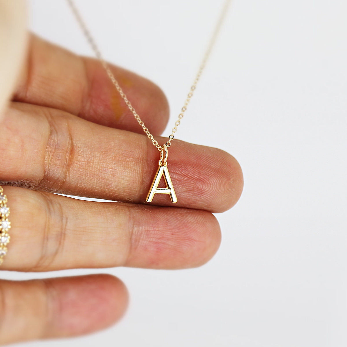 A gold chain necklace with a small gold letter A pendant.