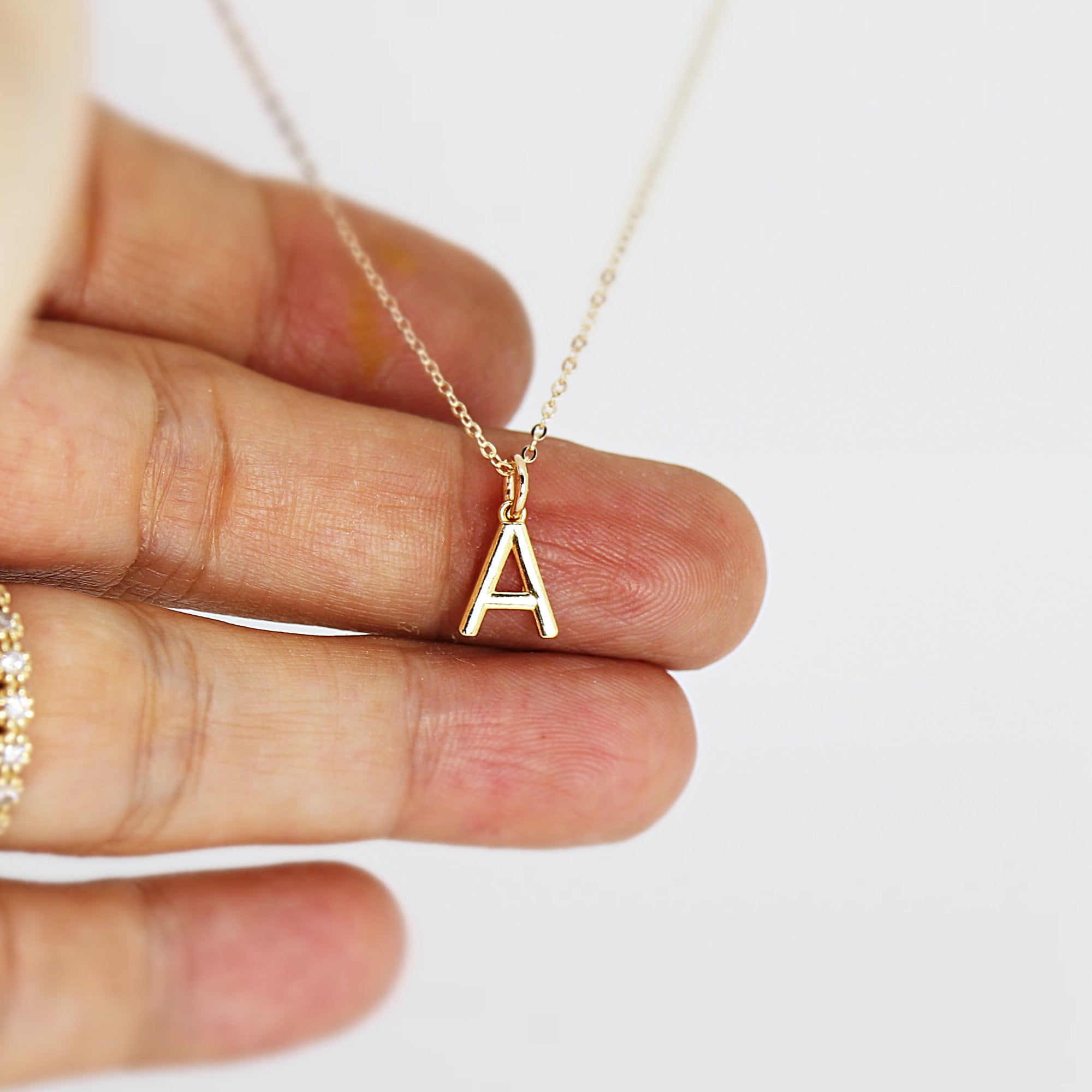 A gold chain necklace with a small gold letter A pendant.