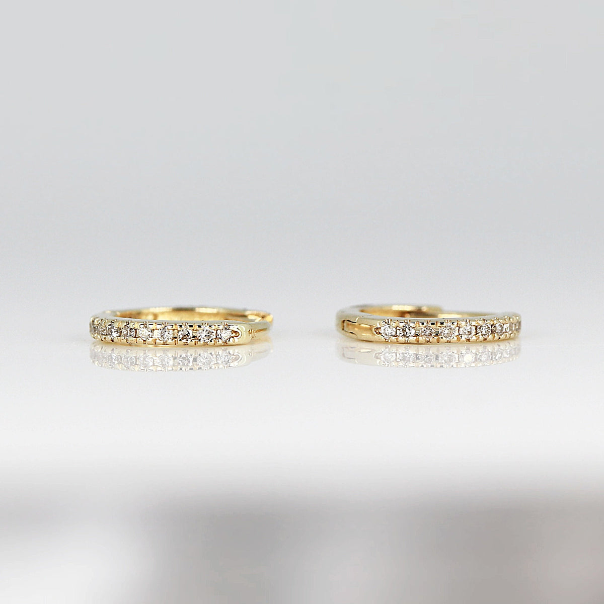 A pair of gold hoop earrings with a single row of small diamonds around the edge.