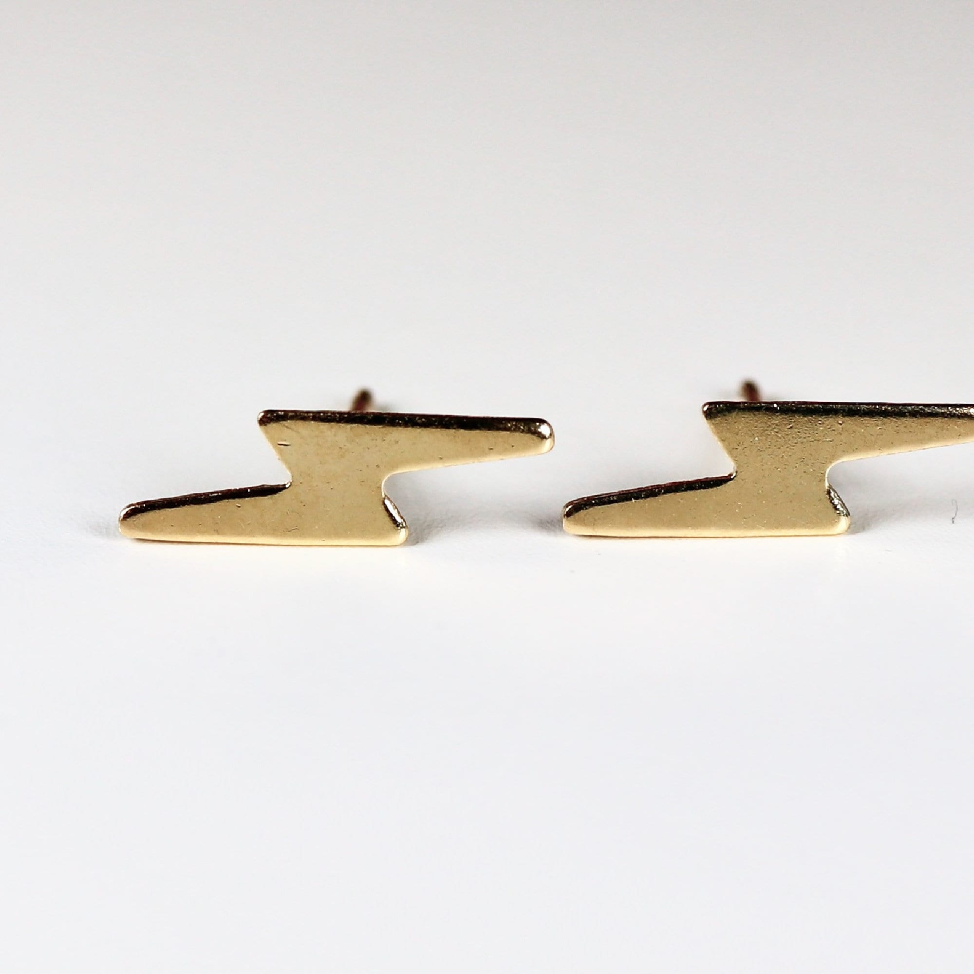 A pair of gold lightning bolt stud earrings.