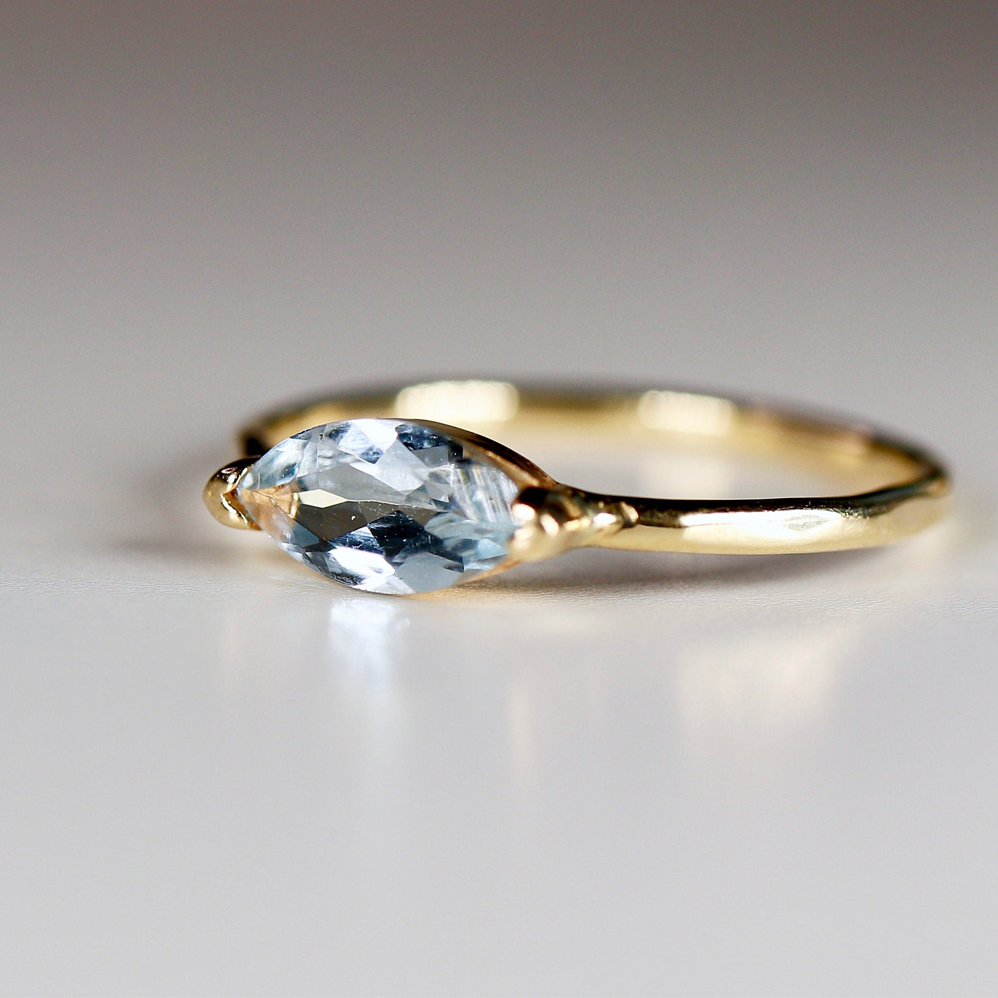 A delicate gold ring with a light blue marquise-shaped aquamarine gemstone.