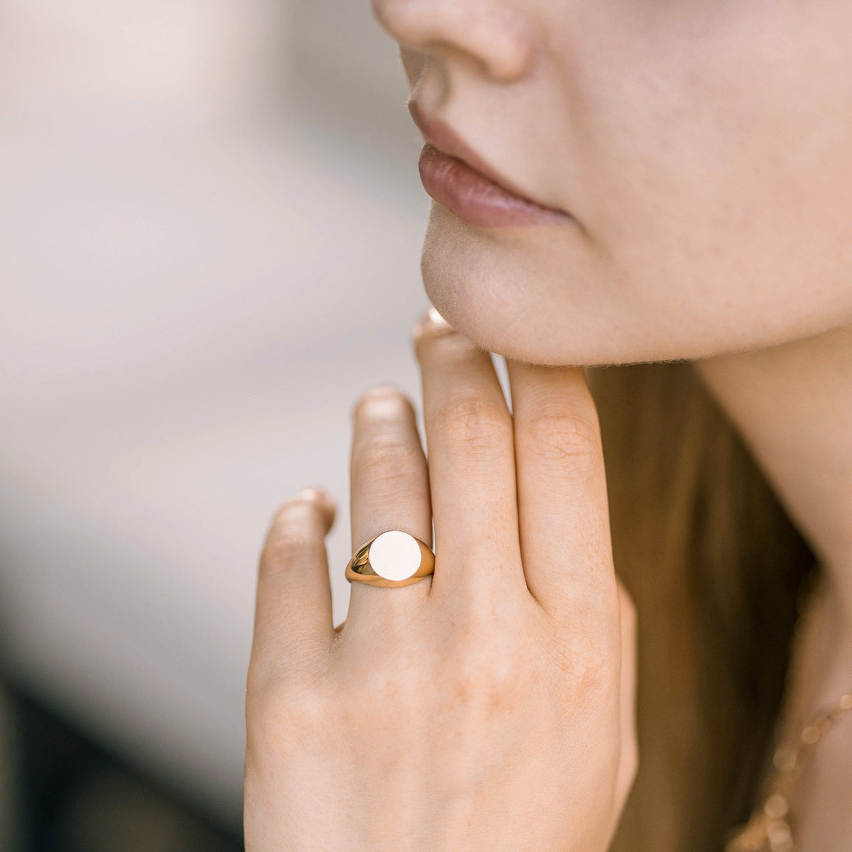 A gold signet ring with a smooth, round, white top. The ring is worn on the finger of a person's hand.