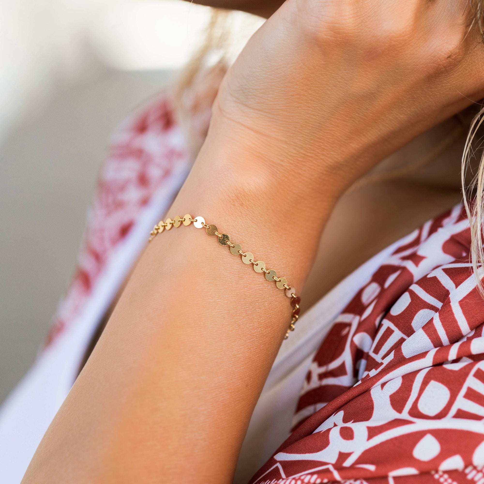 A gold bracelet with a delicate chain and small round discs.
