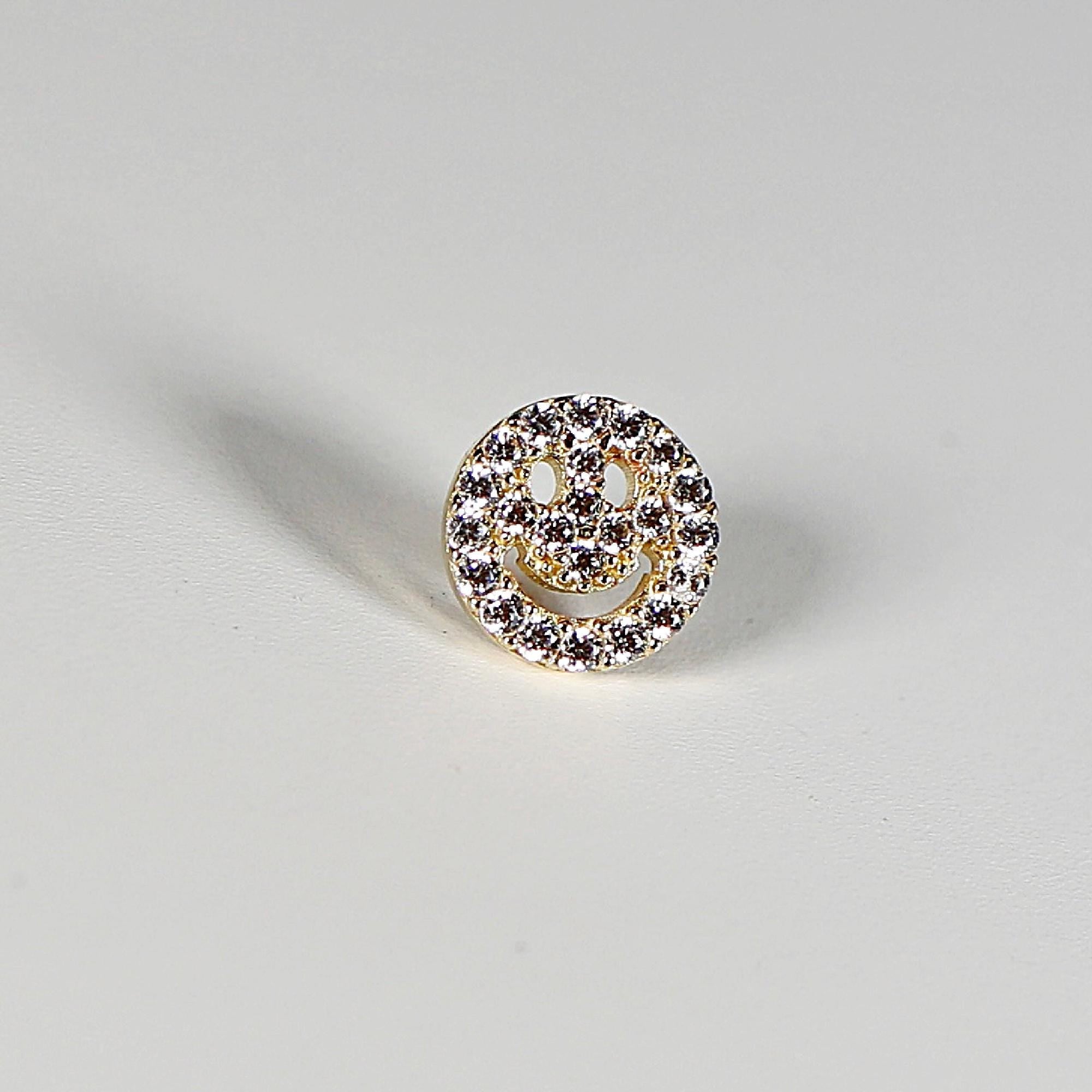 Gold-toned smiley face earring with clear cubic zirconia stones.