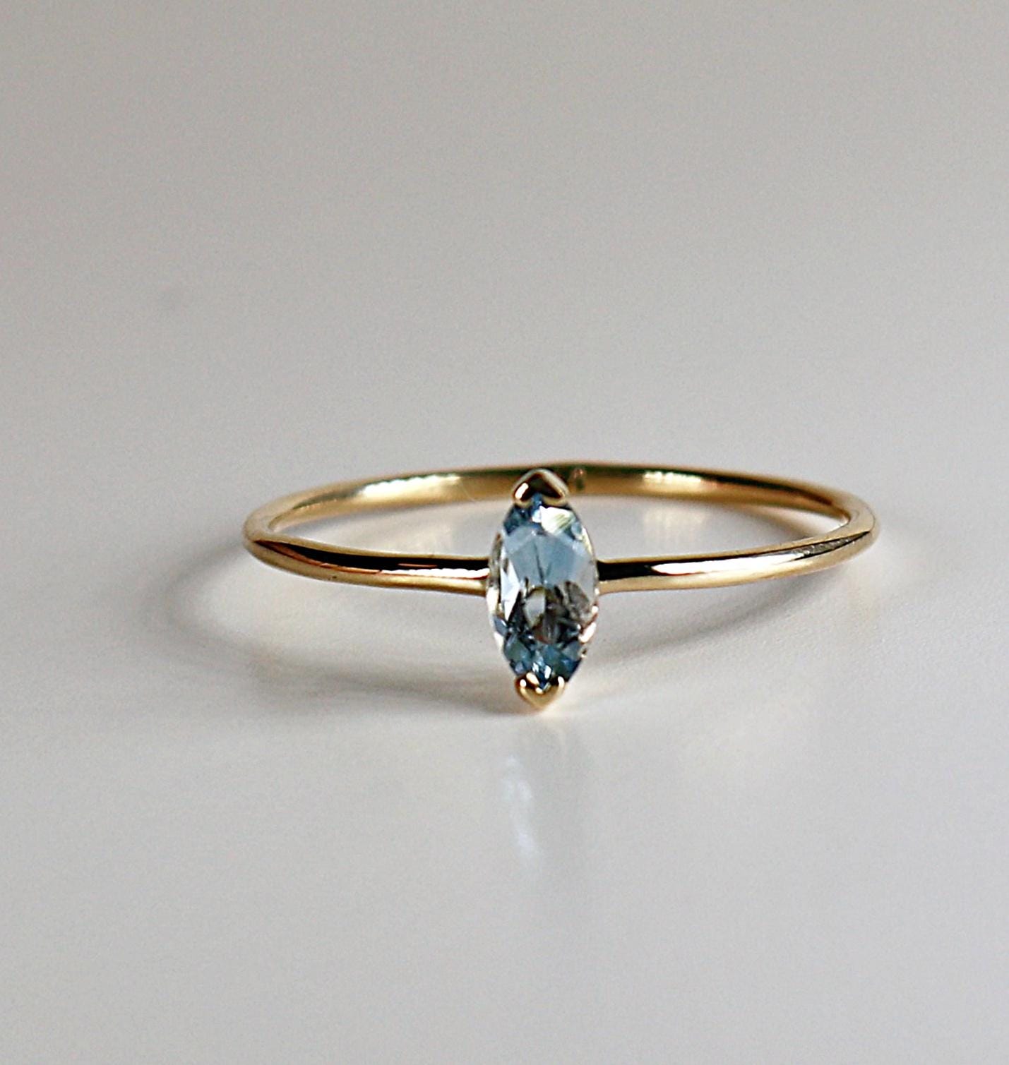 A delicate gold ring with a marquise-shaped aquamarine gemstone.