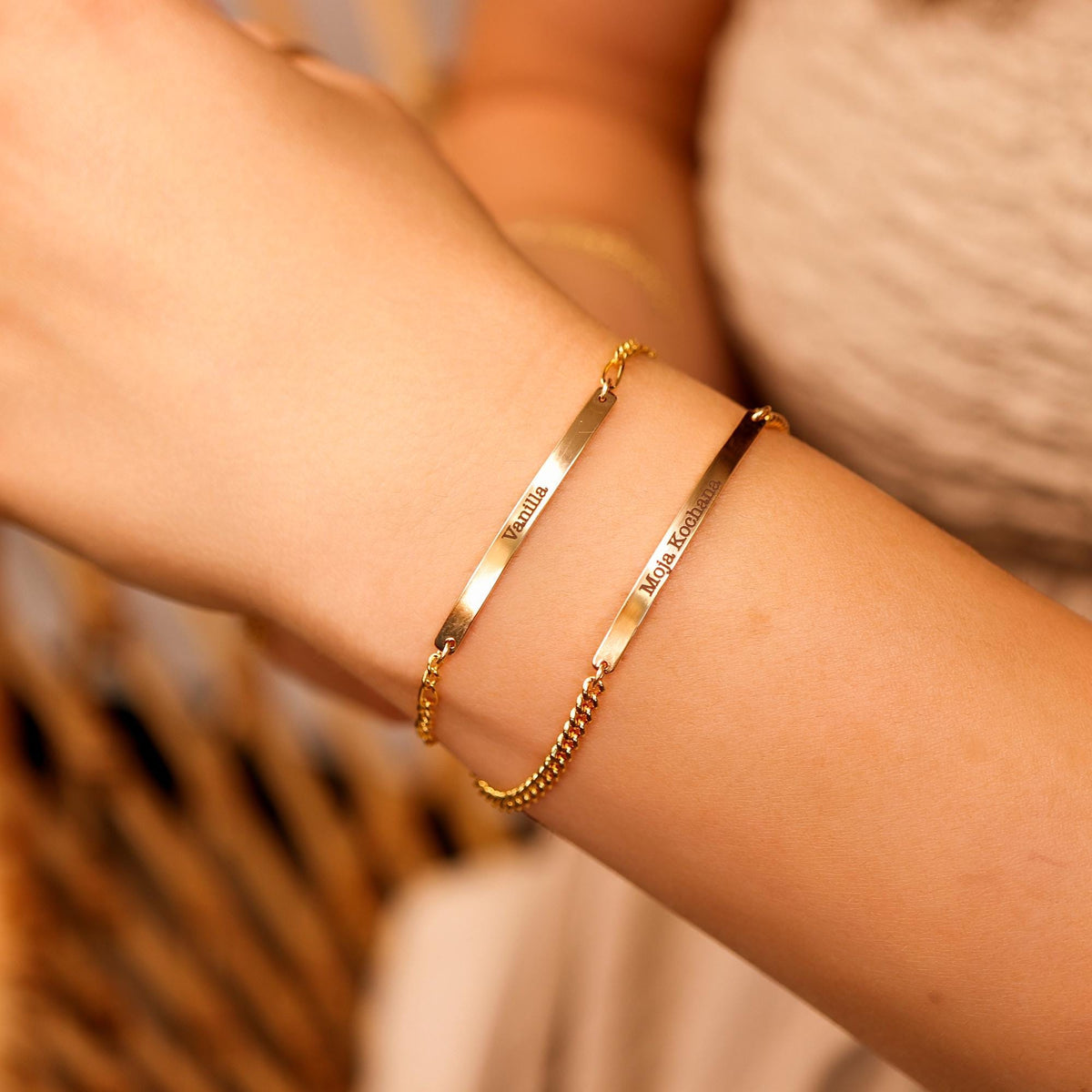A Woman wearing a gold filled bar bracelet with personalized engraving, shown on wrist with a delicate chain and minimalist style.