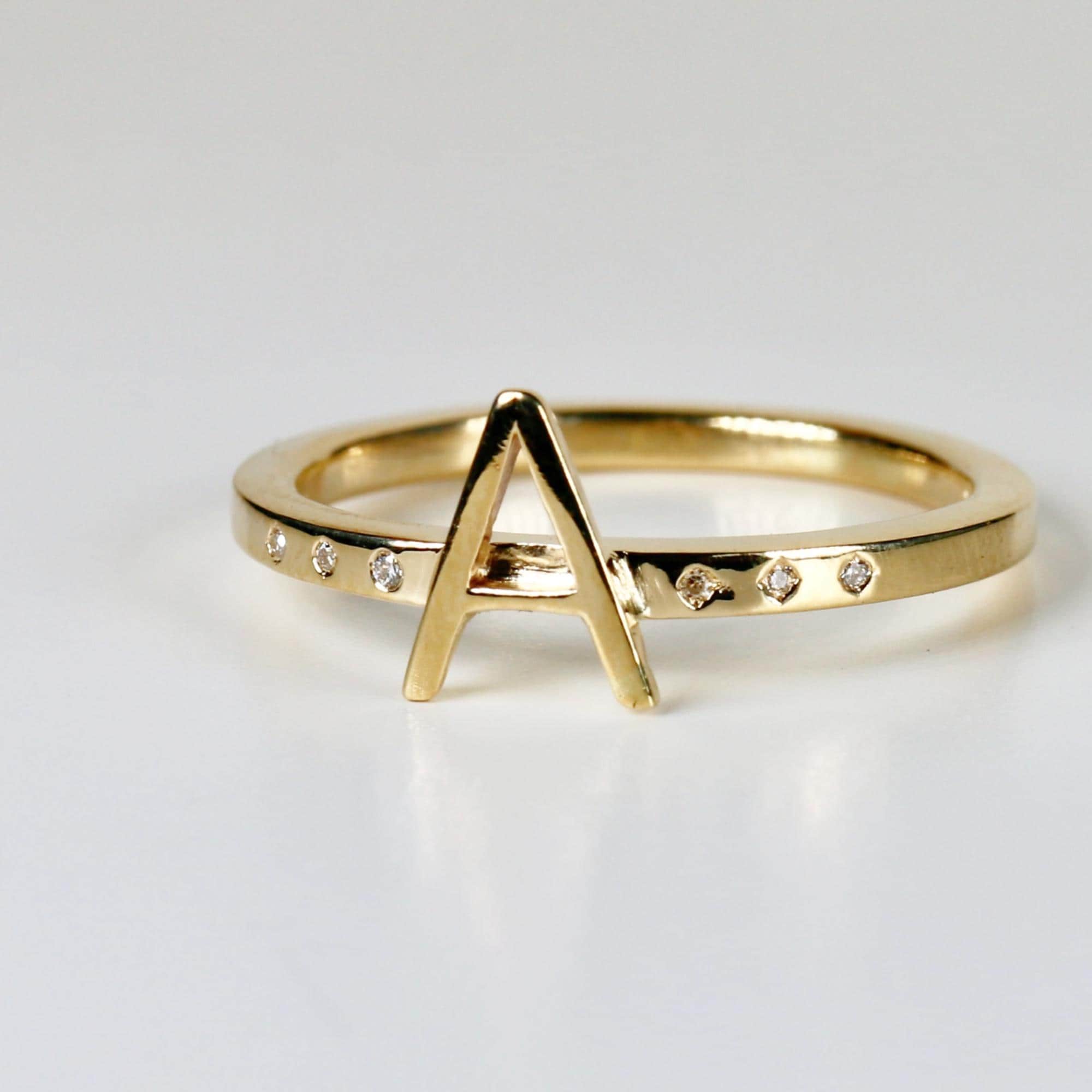 Bold 14k gold initial ring with a modern square band and six scattered diamonds, featuring an 8mm letter on top, shown on white background.