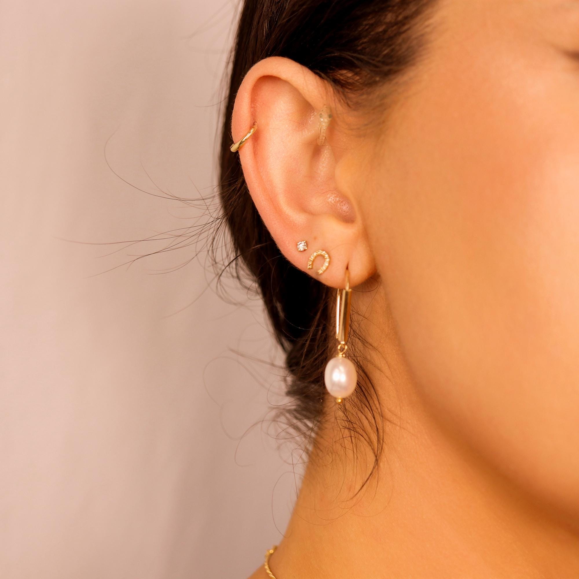 Woman wearing gold filled dangle earrings with large natural baroque pearls, styled as minimalist statement jewelry for bridal or everyday wear.