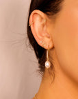 Woman wearing gold filled dangle earrings with large natural baroque pearls, styled as minimalist statement jewelry for bridal or everyday wear.