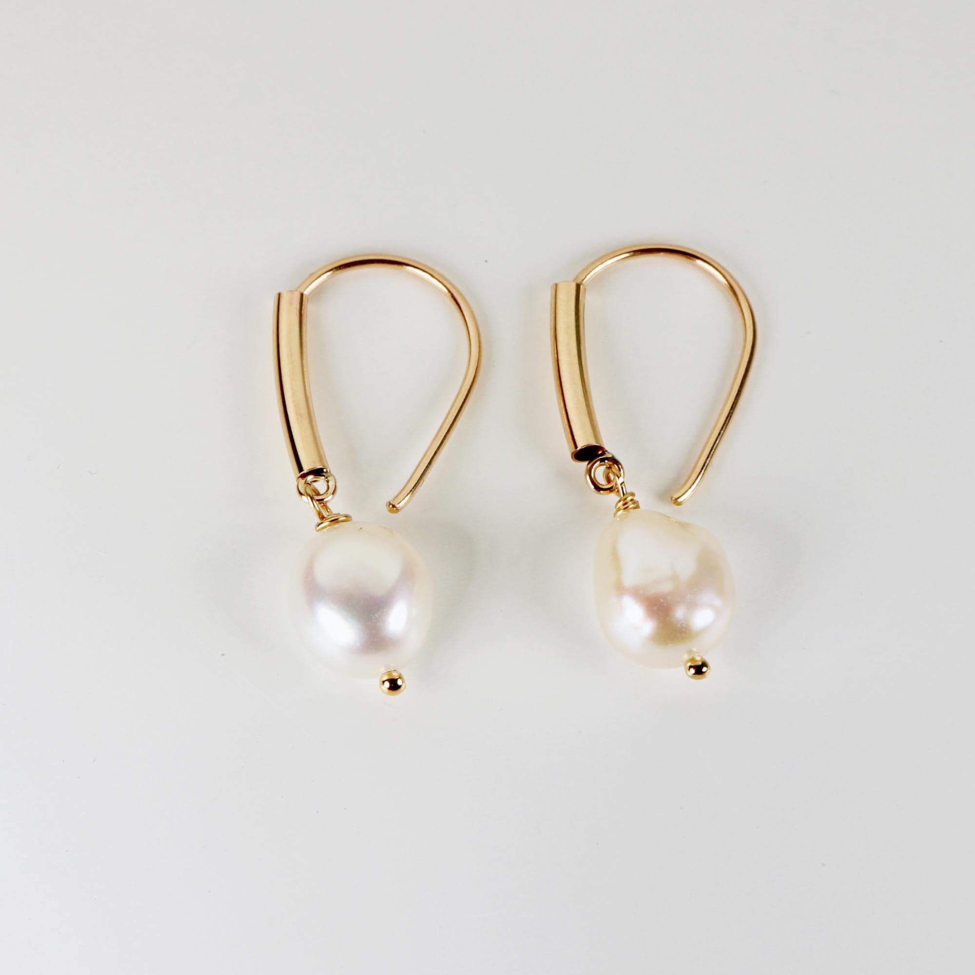 Gold filled dangle earrings featuring large natural baroque pearls with organic shapes, displayed on a white background.