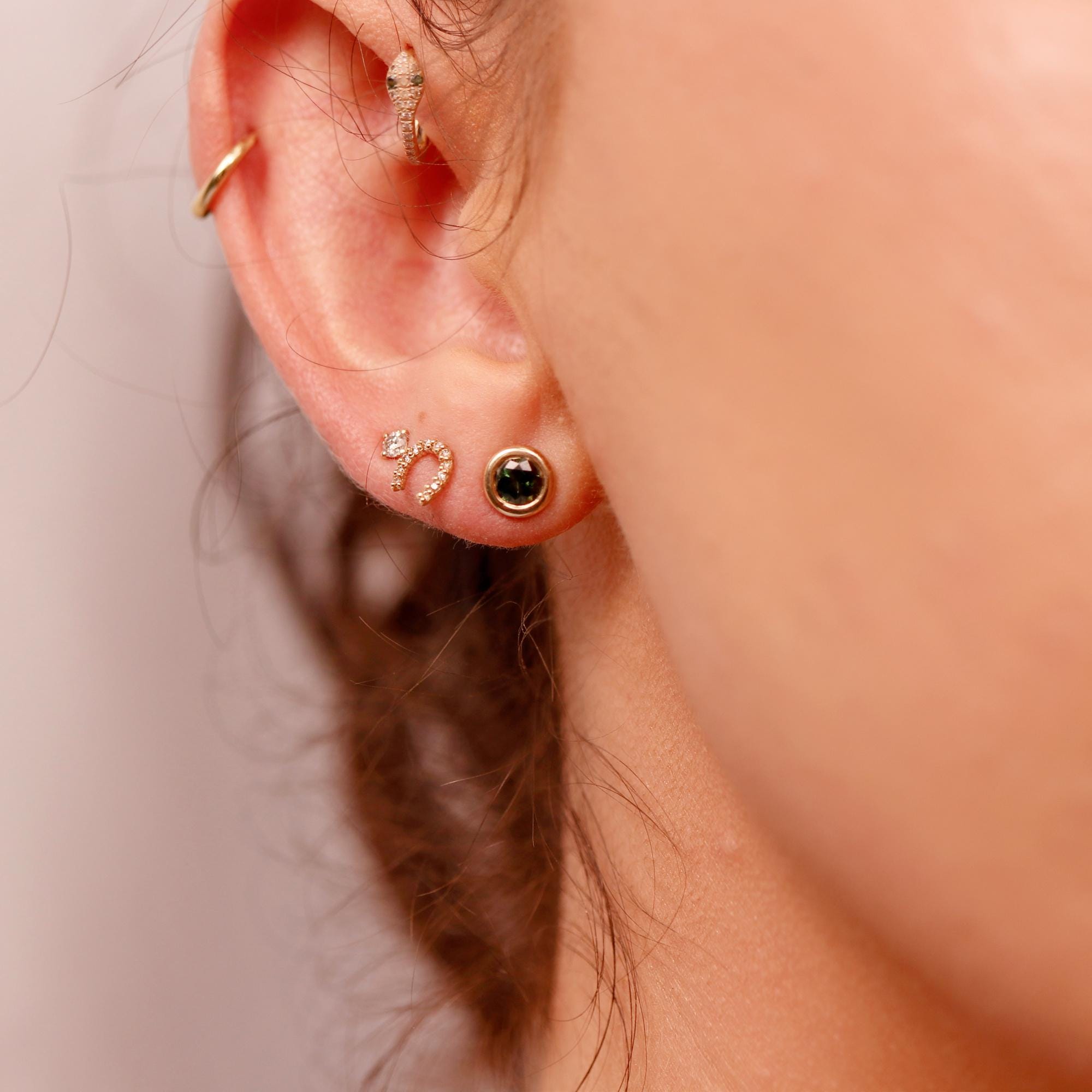 Woman wearing green sapphire bezel stud earrings in 14k gold, styled as bridal or wedding jewelry.