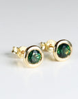 Pair of green sapphire martini bezel stud earrings in 14k solid gold, displayed on a clean white background.