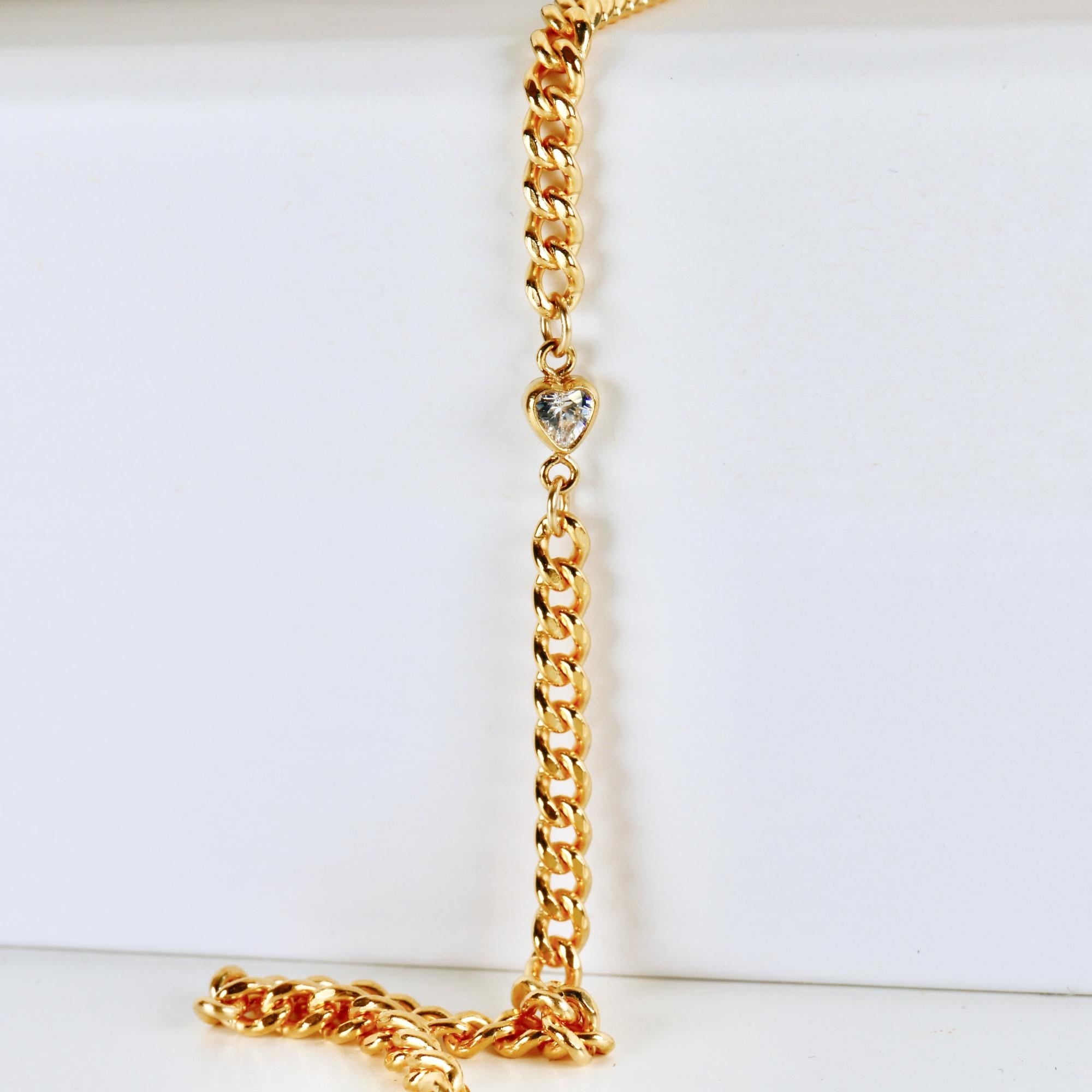 Gold filled curb chain bracelet with a faceted heart-shaped cubic zirconia charm at the center, shown on a white background.