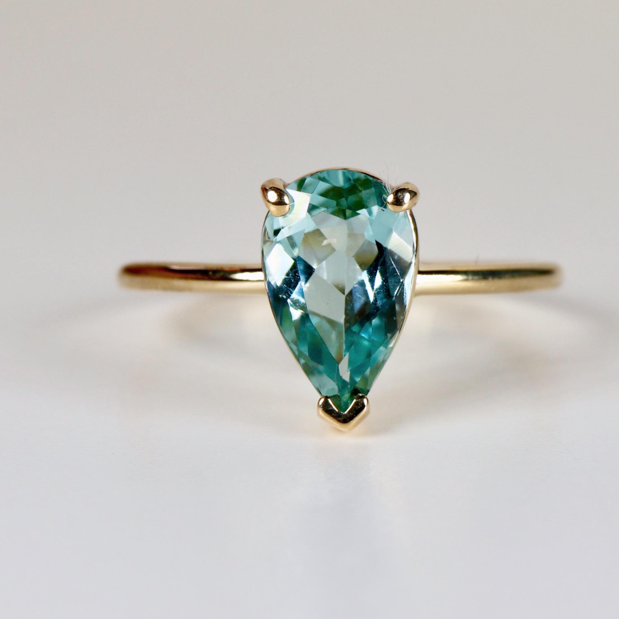 Pear-cut seafoam green tourmaline ring set in solid 14k yellow gold, photographed on a clean white background.