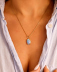 Woman wearing a boulder opal necklace in 14k gold, showing the natural blue fire opal pendant styled as minimalist gemstone jewelry.